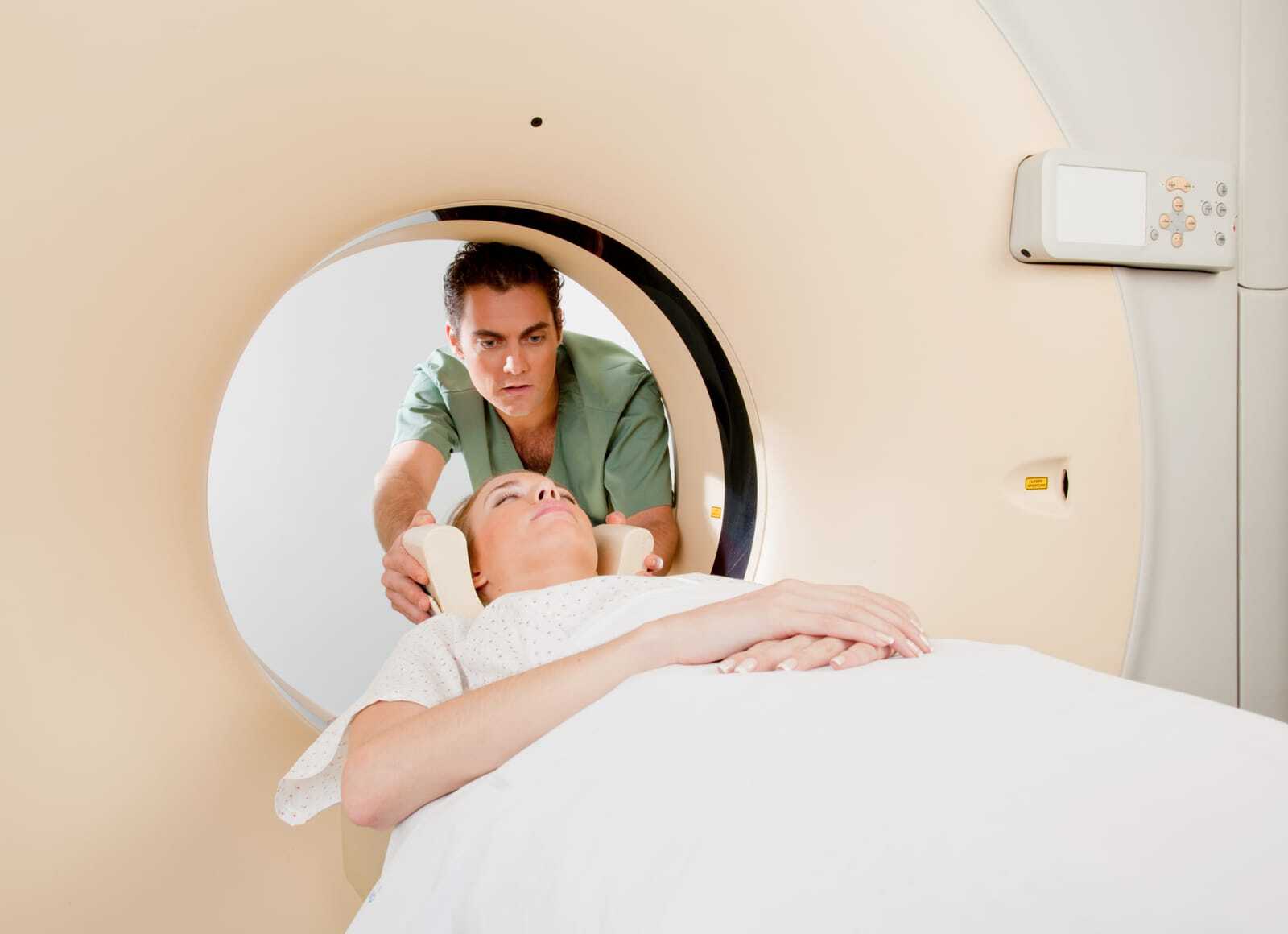 Radiographer positioning a patient’s head in a head holder on a CT scanner table